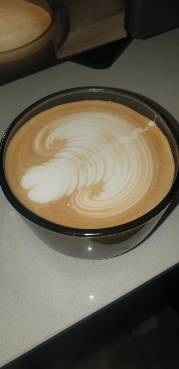 Flat white in a glass cup with swirling latte art