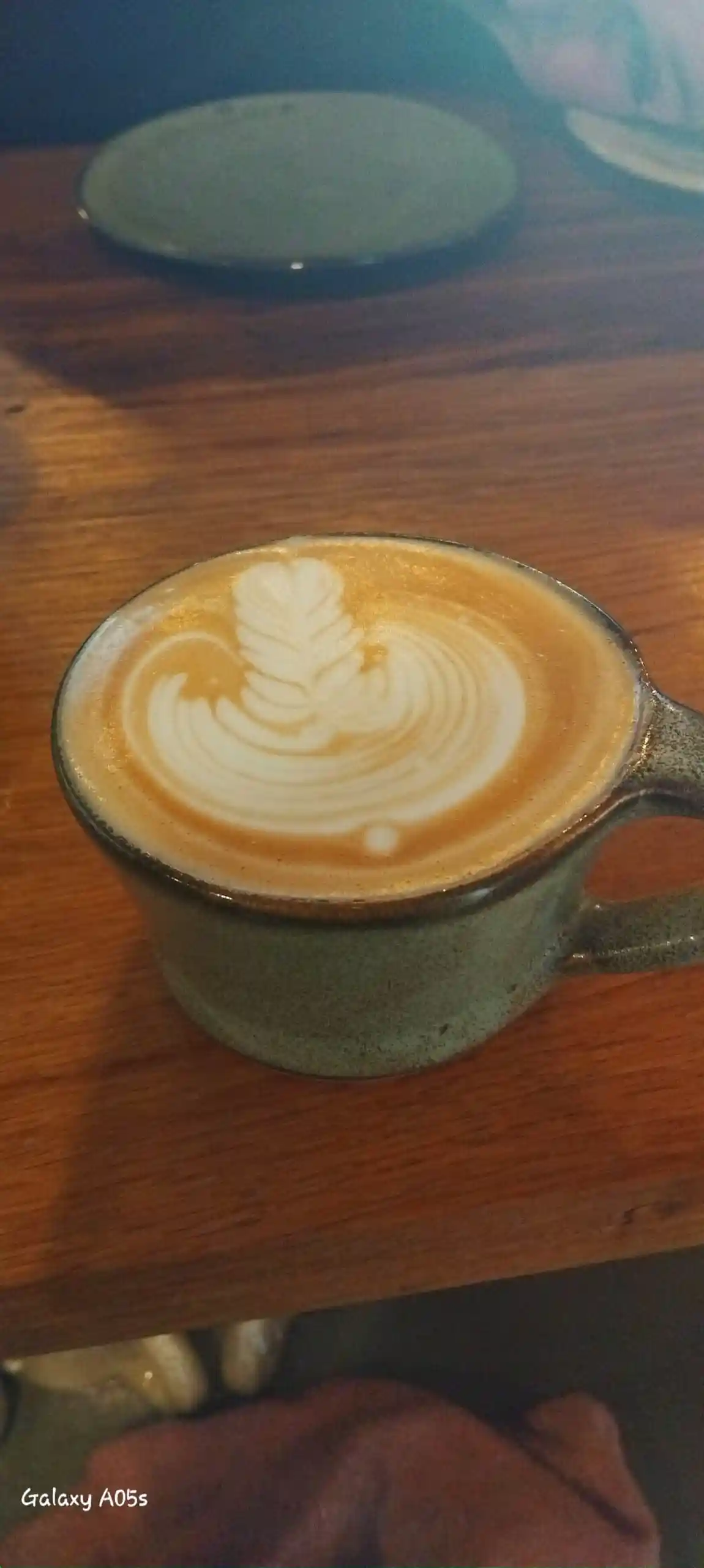 Latte in a rustic ceramic mug on a warm wooden table