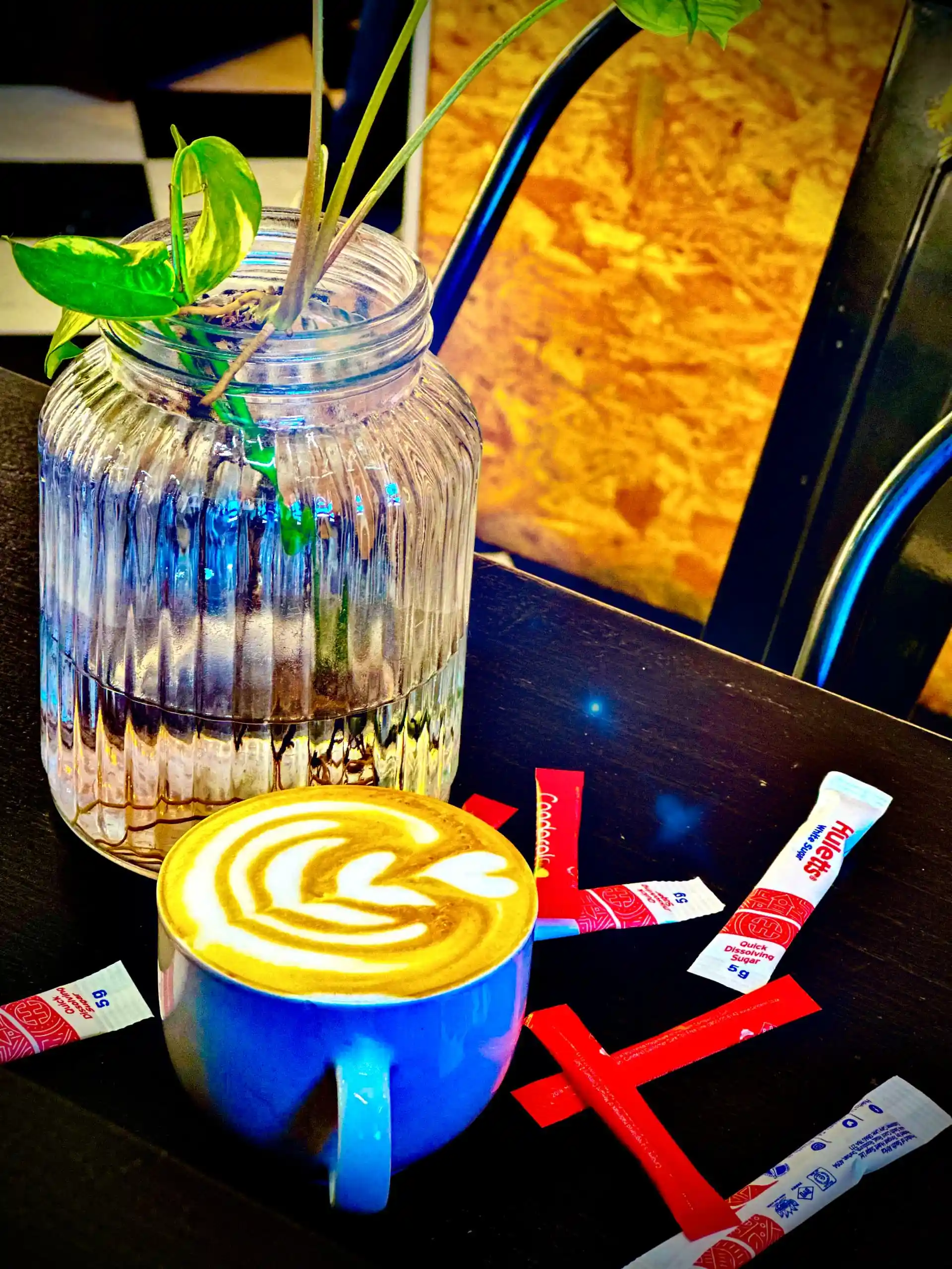 Latte in a blue mug with Huletts sugar sticks scattered around