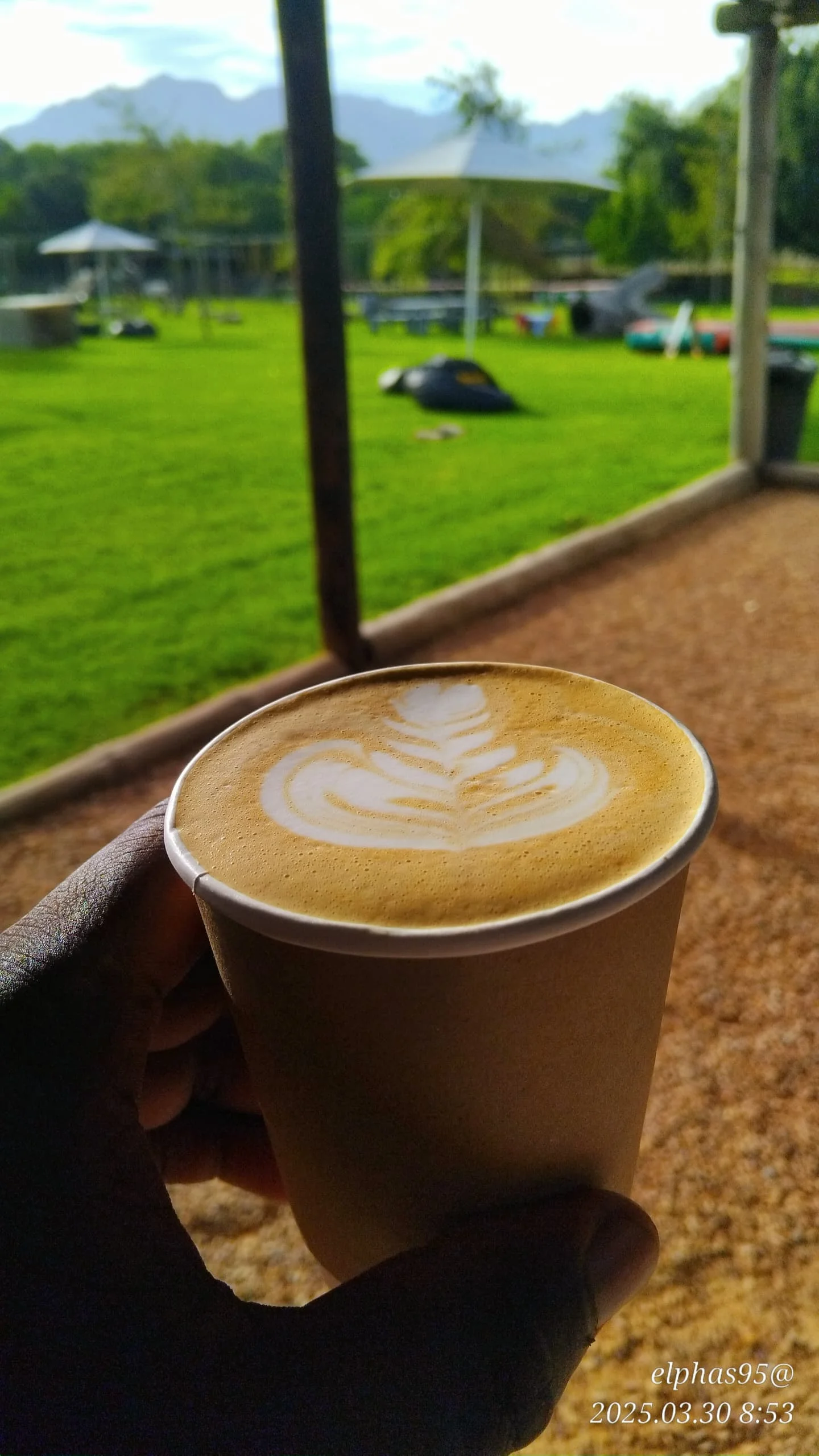 EL-J Coffee latte in a takeaway cup against mountain scenery