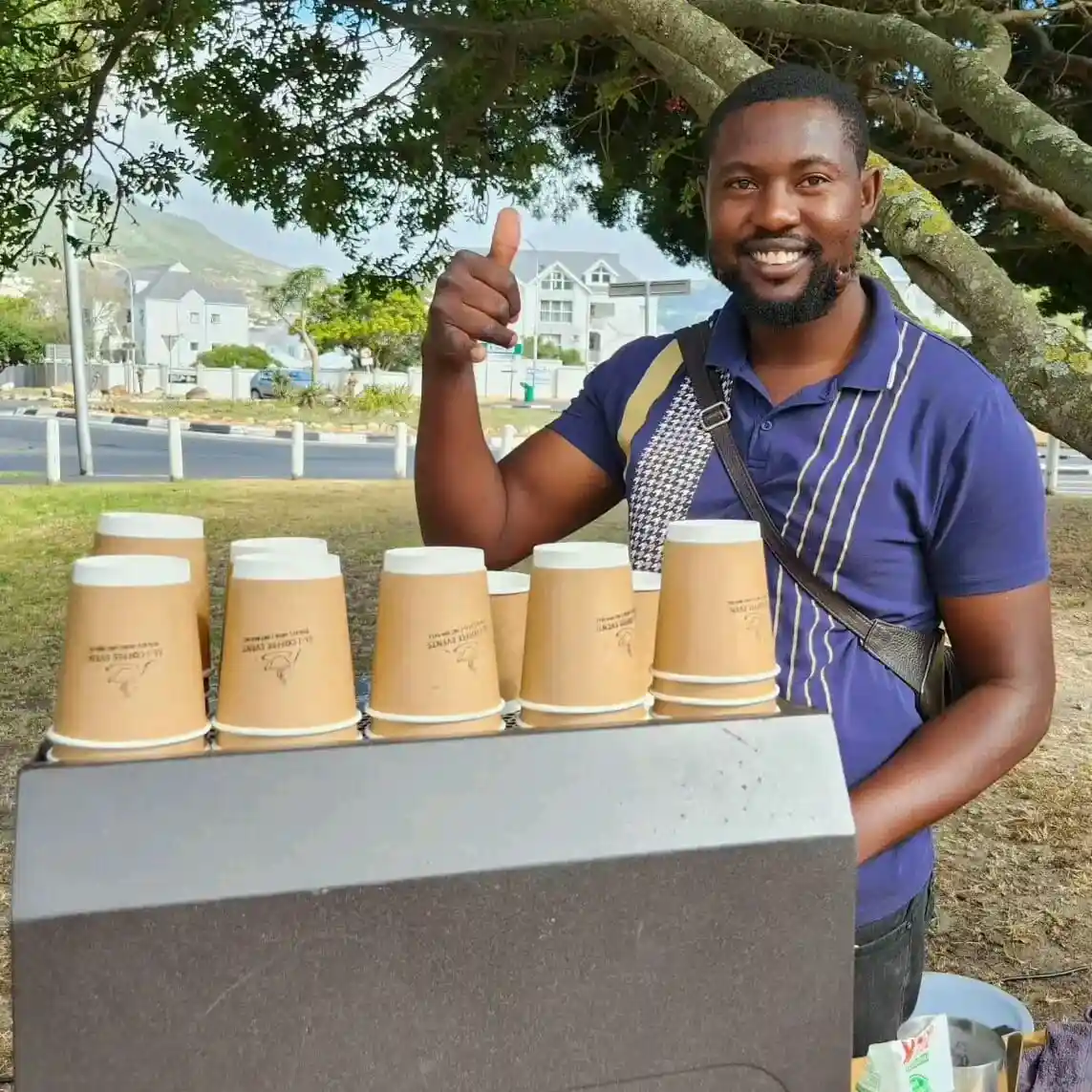 EL-J Coffee barista at an outdoor stand with branded paper cups